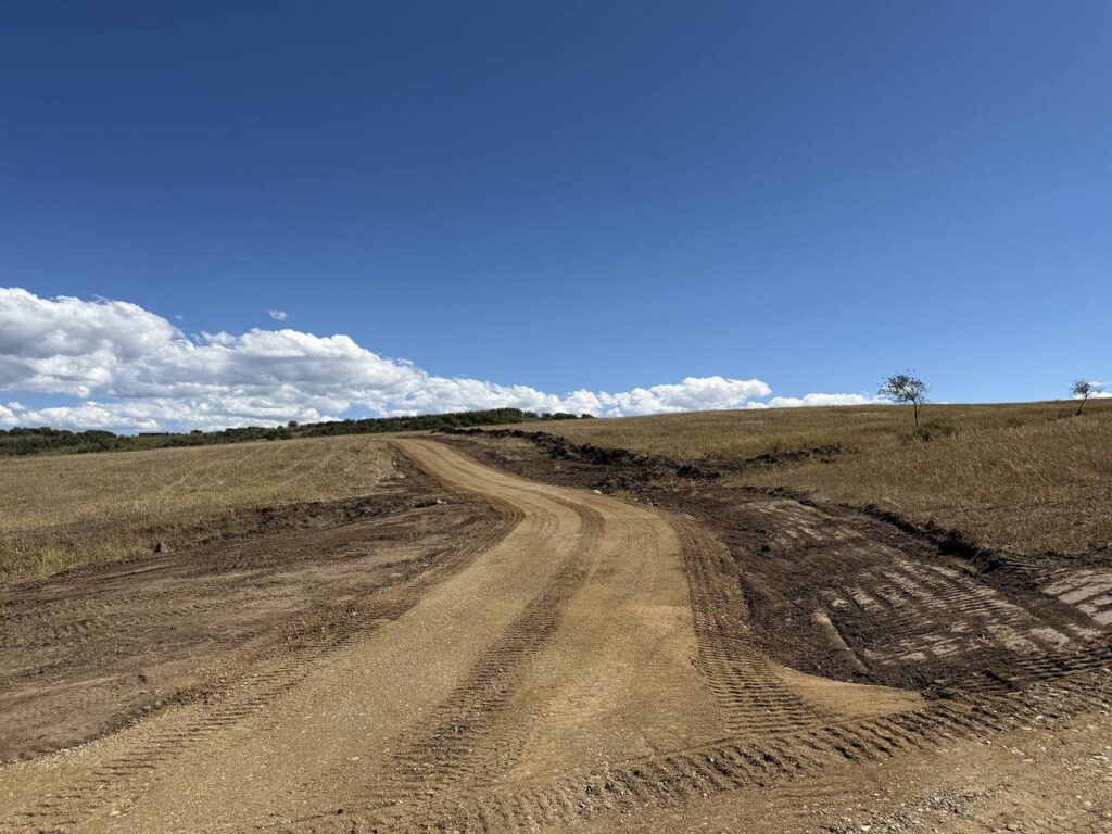 Graded private access road running up toward the ridge with topsoil windrowed along the edge